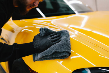 Cleaner worker dry body car using microfiber after washing automobile. Hand car drying with...