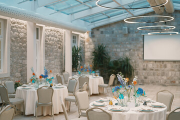 Montenegro, Budva - July 01, 2024: Festive laid tables in a restaurant with glowing round lamps on the ceiling