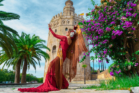 Mujer t&iacute;pica espa&ntilde;ola bailando flamenco con una torre medieval y el cielo a su espalda. Desde la ciudad de Sevilla, Andaluc&iacute;a, Espa&ntilde;a, Europa.	