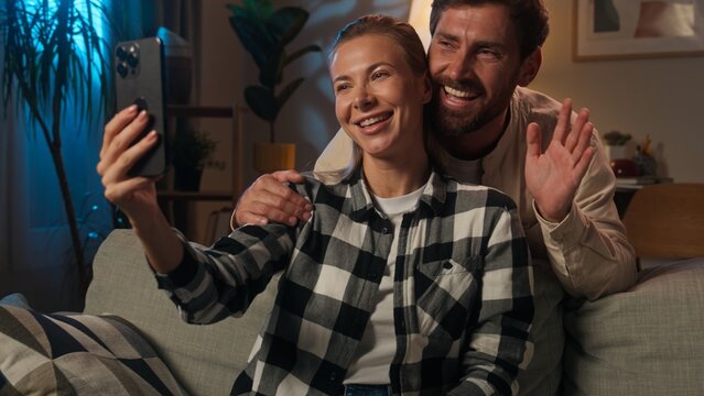 Happy family bloggers influencers love couple Caucasian woman man girl guy husband wife talk video call online chat smartphone record blog selfie vlog mobile phone addict social media at evening home