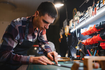 Working process of the leather belt in the leather workshop. Man holding crafting tool and working