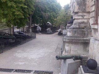 Serene Courtyard with an Array of Old Cannons and Military Artifacts Under Tree Canopy