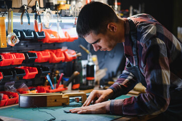 Man working with leather. Professional makes a wallet.