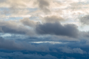 Obraz premium Stormy sky with dark, snowy clouds on a spring day. Clouds are floating across the sky. Dramatic clouds. Dark blue clouds swiftly floating across blue sky. Sky texture, abstract nature background.