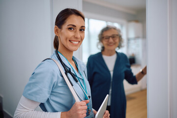 Fototapeta premium Happy nurse visiting senior woman at home and looking at camera.