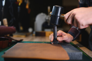 Man working with leather. Professional makes a wallet.