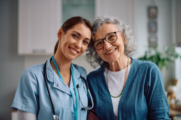 Happy senior woman and nurse during home visit looking at camera.