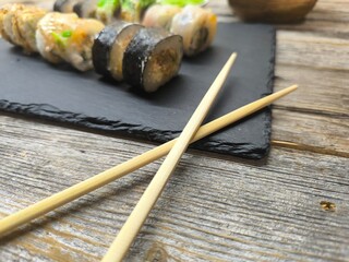 Close-up of various sushi lying on granite board next to wooden chopsticks