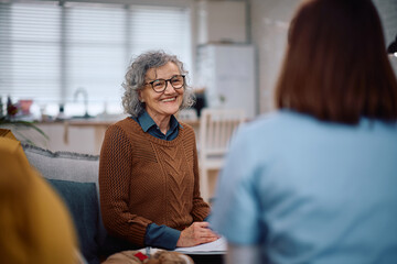 Happy senior woman talking to caretaker who is visiting her at home.