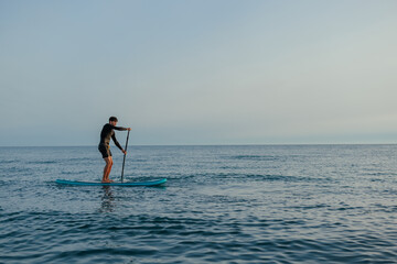 Man paddleboarding at sunset
