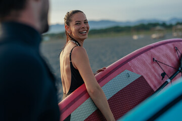 Attractive brunette carrying a pink paddleboard
