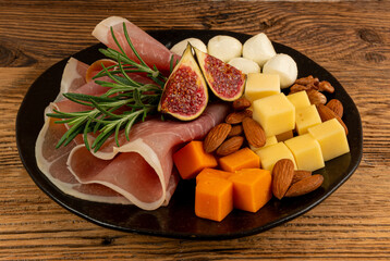 Cheese plate with prosciutto, jamon cut, parma ham, serrano slices, cured iberico closeup, cheese board
