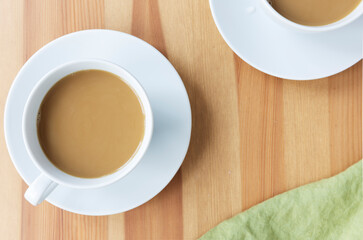 Flat Lay of coffee in white mug on liight wood table.