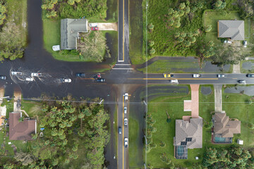 Hurricane flooded street with moving cars and surrounded with water houses in Florida residential...