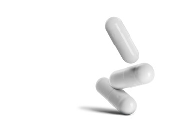 Three medical pills falling on white background