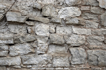 A wall made of limestone stones. The stones have crumbled in the wall of the building due to time and weather. The wall was built from the stones in ancient times.