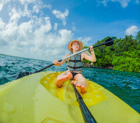 Unaltered woman tourist kayaking on the serene turquoise waters of Lake Bacalar, Mexico, surrounded by natural beauty. Adventure, relaxation, and outdoor travel concept in a peaceful tropical