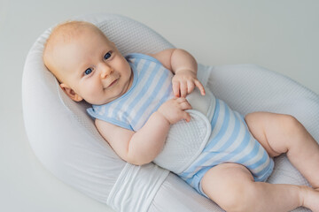 Adorable 3-month-old baby lying safely in a cozy infant cocoon secured with a special safety belt....
