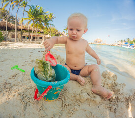 Toddler playing on the beach with a bucket and spade. Joyful childhood, seaside fun, and summer vacation concept. © galitskaya