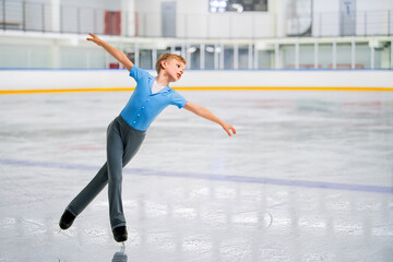 A young boy figure skater skates on the ice of an indoor ice arena © Maria Moroz