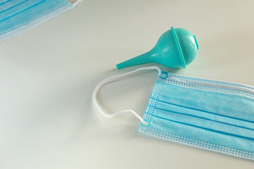 Disposable mask on a white background, close-up, and a syringe with a soft tip lies nearby. Medical background. Space for text. Items used in the medical industry.