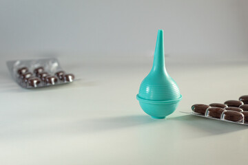 Syringe with soft tip and in the background tablets/vitamins in blisters. Medical background.