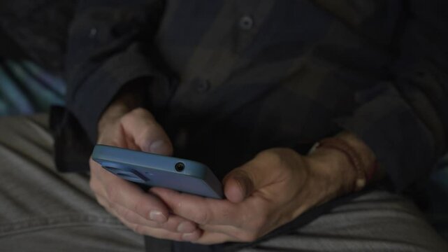 horizontal detail video of man's hands browsing mobile phone on the sofa