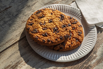 A large homemade cookie on a table – a symbol of coziness, family traditions, and warm moments. The warm sunlight and sweet taste of chocolate – cookies as a symbol of enjoying simple moments.