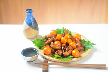 木製プレートに鶏モツ煮込み料理を盛り付けと日本酒