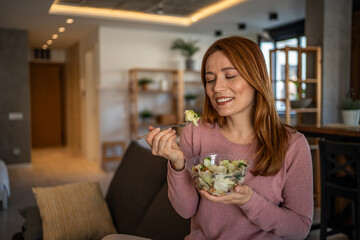 Happy woman eating healthy salad at home