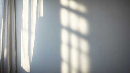 Light from the window illuminates the white wall, casting shadows from the curtain, creating blurry shapes and silhouettes on the wall.