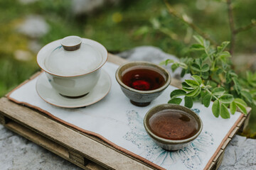 Tea ceremony scene featuring a traditional Chinese tea set resting on a smooth, natural wooden tea...