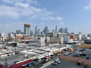 Downtown Los Angeles skyline seen from the Fashion District, with parking lots in the foreground. Blue sky with a few puffy clouds