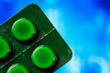 Close-up of green tablet blister pack against a vibrant blue background