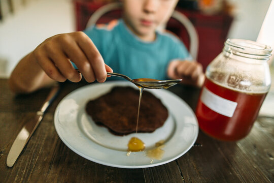 Boy spooning honey on breakfast