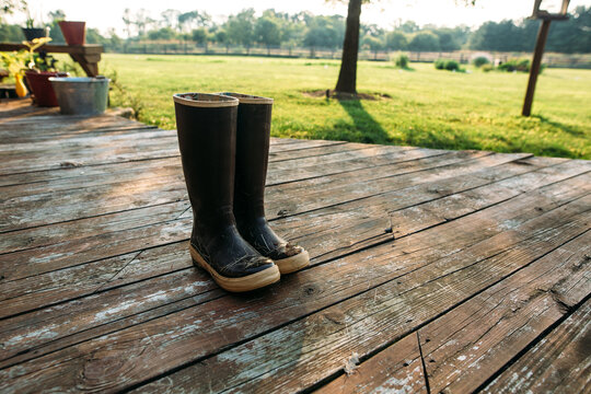 Photo of boots on a deck with farm in background
