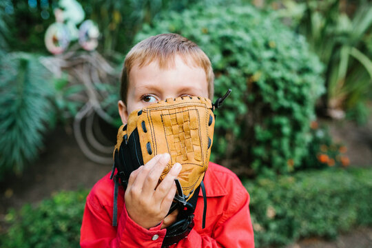Little boy with baseball glove covering face
