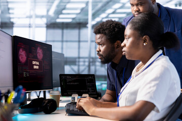 Engineer in server hub helped by coworkers to investigate breach alerts, working to protect...