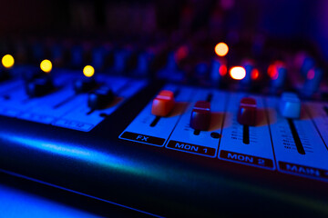 dark blue close up audio mixer control board knobs and buttons studio recording equipment