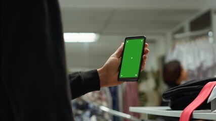Middle eastern man uses green screen and arranging accessories on display at a clothing store,...
