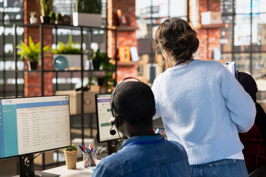 Customer service manager supervising agents logging customer interactions in CSM system. Call center supervisor overseeing workers using customer service management software - Powered by Adobe