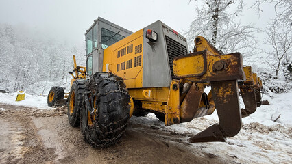 A lone bulldozer pushes through thick snow, breaking the silence of this remote winter wonderland
