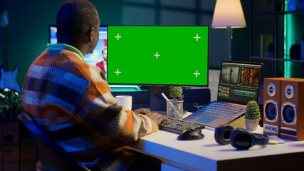 Videographer creating visual effects on montage next to green screen, working on color correction to edit footage and frames. Freelancer content creator editing clips on computer software. Camera A.