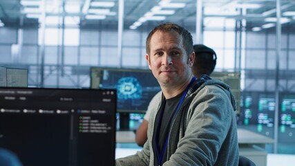 Portrait of joyous IT expert in server farm ensuring valuable data remains shielded from threats....