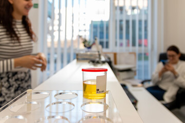 A young beautiful  woman hands over an urinalysis in a laboratory. Health care and medical concept.