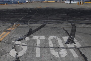 Cracked asphalt road with a large white stop sign and tire skid marks at an urban intersection emphasizing traffic safety and road conditions