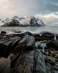 Sunrise at Vareid beach with snow-covered mountains, Flakstadpollen fjord, Lofoten, Norway