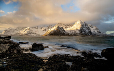 Sunrise at Vareid beach with snow-covered mountains, Flakstadpollen fjord, Lofoten, Norway