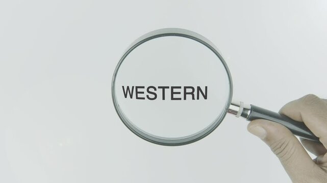 Western text or word highlighted by a magnifying glass in a hand on a white background, symbolizing culture, heritage, and the influence of the Western world, often linked to history, values