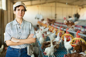 Portrait of positive highly experienced latin adult woman working in chicken farm